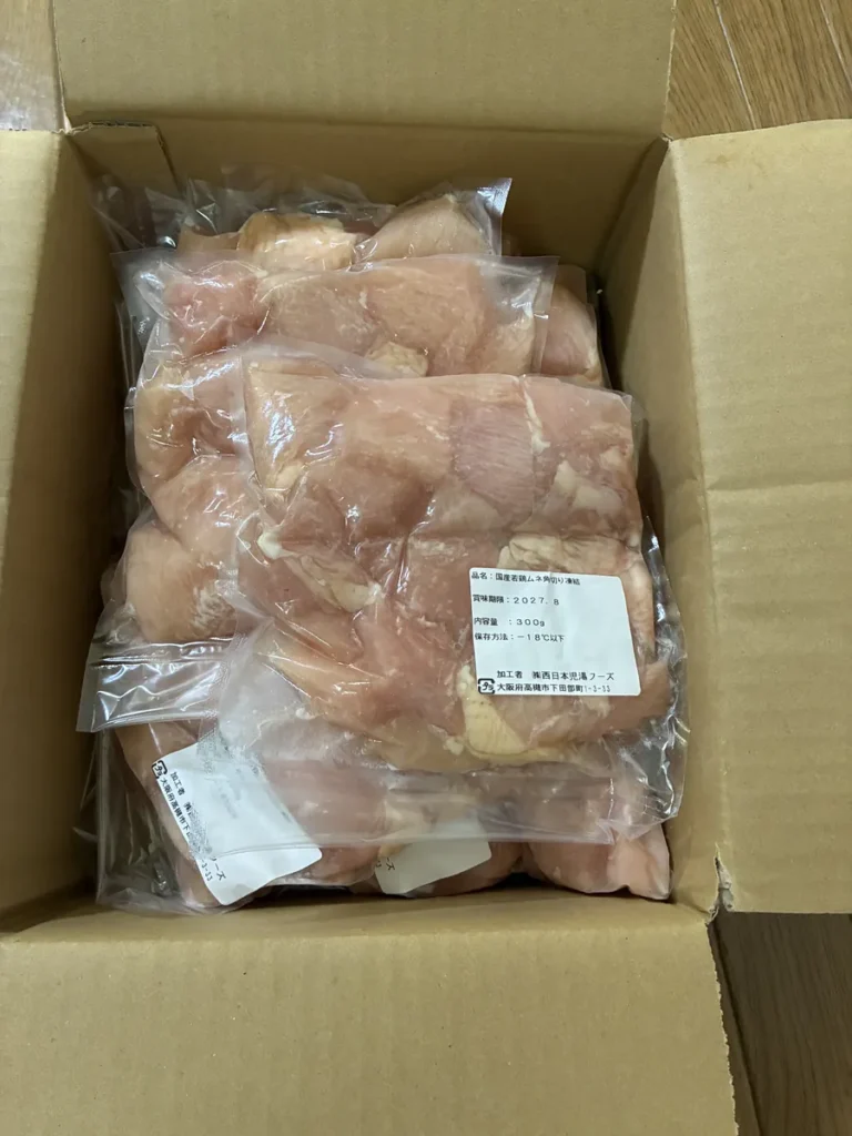 段ボール箱の中に、角切りの鶏むね肉が入った透明な袋が重なって入っている
